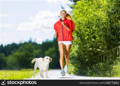 Sport girl. Young attractive sport girl running with dog in park
