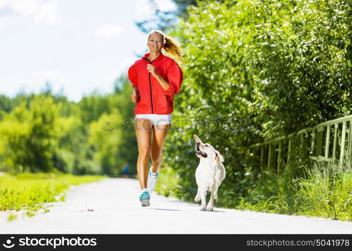 Sport girl. Young attractive sport girl running with dog in park