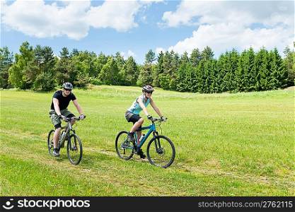 Sport happy couple riding bicycles in coutryside meadows