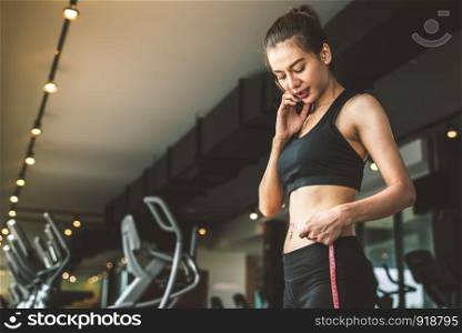 Sport happy slim woman using waist tape line in fitness gym sport club training center background. Success lifestyle of people workout exercise activity. Diet and weight loss