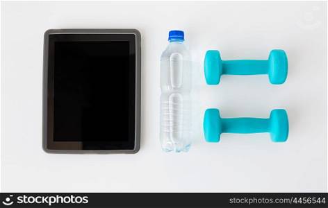 sport, healthy lifestyle and objects concept - close up of tablet pc computer with dumbbells and water bottle over white background