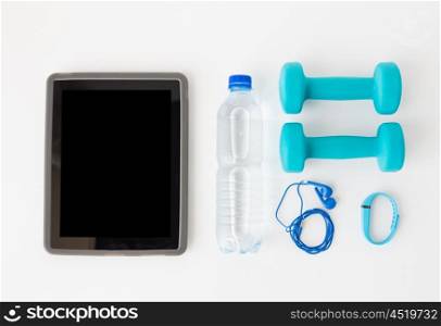 sport, healthy lifestyle and objects concept - close up of tablet pc computer with dumbbells, fitness tracker, earphones and water bottle over white background