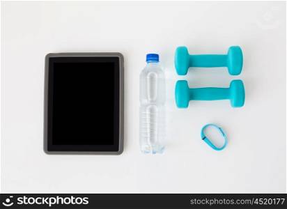 sport, healthy lifestyle and objects concept - close up of tablet pc computer with dumbbells, fitness tracker and water bottle over white background
