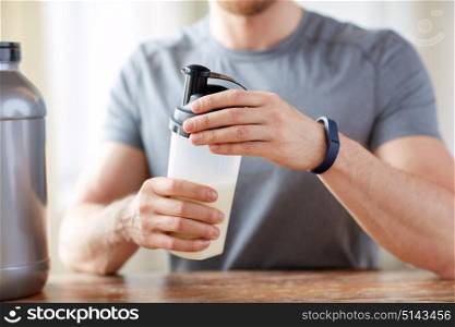 sport, healthy lifestyle and people concept - close up of man wearing fitness tracker with jar and bottle preparing protein shake. close up of man with protein shake bottle and jar