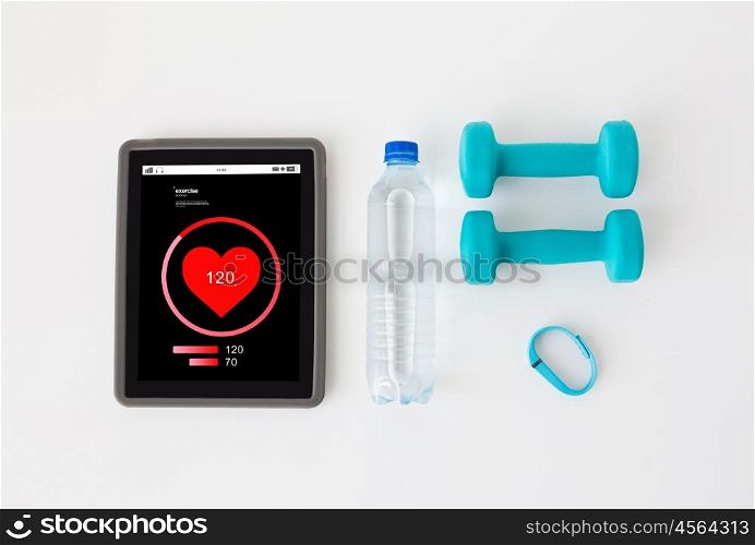 sport, healthy lifestyle, fitness and technology concept - close up of tablet pc computer heart rate on screen, dumbbells with fitness tracker and water bottle over white background