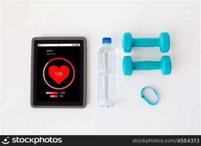sport, healthy lifestyle, fitness and technology concept - close up of tablet pc computer heart rate on screen, dumbbells with fitness tracker and water bottle over white background