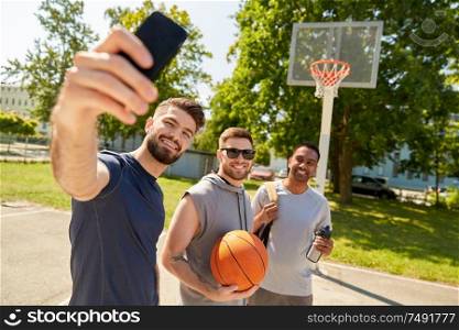 sport, leisure games and male friendship concept - group of happy men or friends taking selfie on outdoor basketball playground. happy men taking selfie on basketball playground