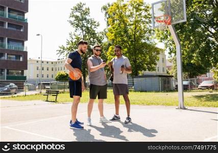 sport, leisure games and male friendship concept - group of men or friends with smartphone at outdoor basketball playground. men with smartphone at basketball playground