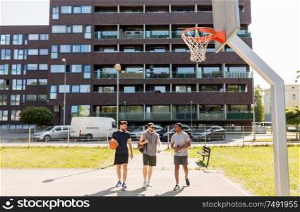 sport, leisure games and male friendship concept - group of men or friends going to play basketball outdoors. group of male friends going to play basketball