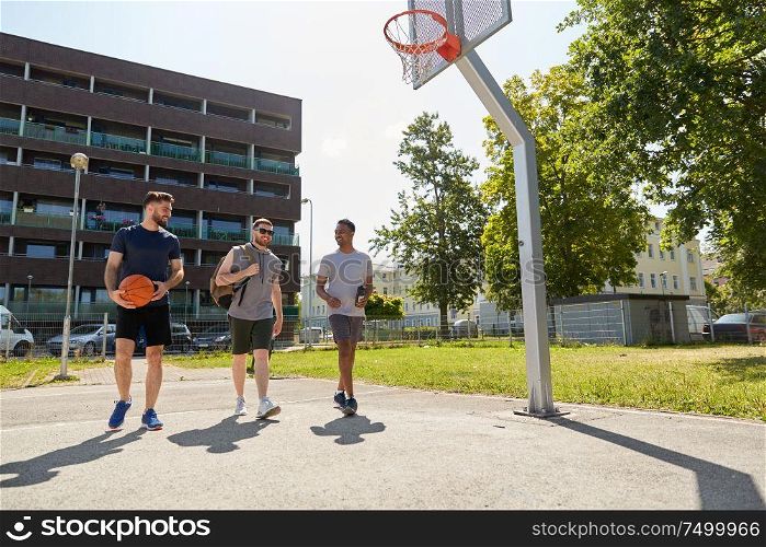 sport, leisure games and male friendship concept - group of men or friends going to play basketball outdoors. group of male friends going to play basketball