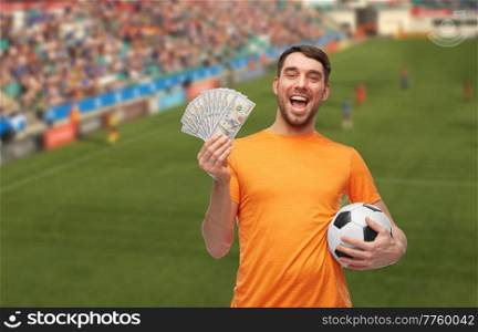 sport, leisure games and online betting concept - happy smiling man or football fan with soccer ball and money over stadium background. happy football fan with soccer ball and money