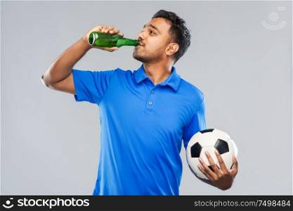 sport, leisure games and people concept - happy indian man or football fan with soccer ball and beer bottle over grey background. indian male football fan with soccer ball and beer