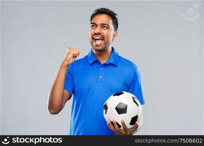 sport, leisure games and success concept - happy indian man or football fan with soccer ball celebrating victory over grey background. football fan with soccer ball celebrating victory