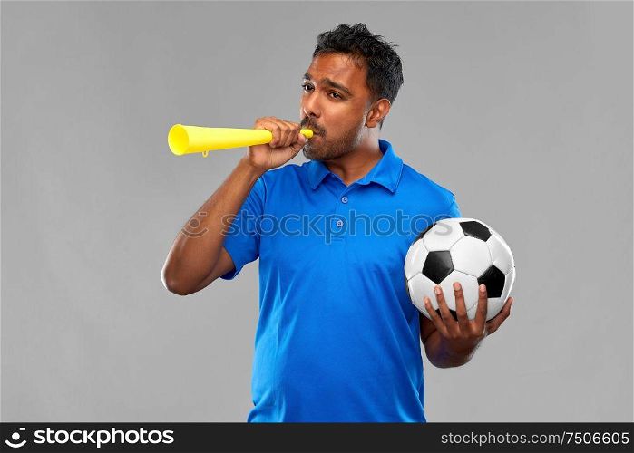 sport, leisure games and success concept - indian man or football fan with soccer ball blowing vuvuzela over grey background. male football fan with soccer ball and vuvuzela