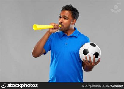 sport, leisure games and success concept - indian man or football fan with soccer ball blowing vuvuzela over grey background. male football fan with soccer ball and vuvuzela
