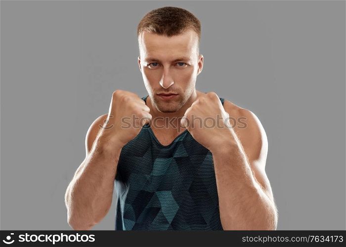 sport, martial arts and people concept - portrait of young man boxing or showing his fists. young man or bodybuilder showing his fists