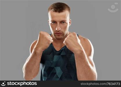sport, martial arts and people concept - portrait of young man boxing or showing his fists. young man or bodybuilder showing his fists
