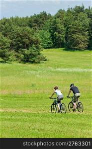Sport mountain biking happy couple riding downhill in sunny countryside