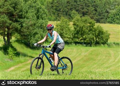 Sport mountain biking happy girl riding uphill in sunny countryside