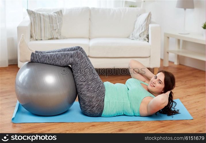 sport, people and healthy lifestyle concept - happy plus size young woman exercising with fitness ball on mat at home