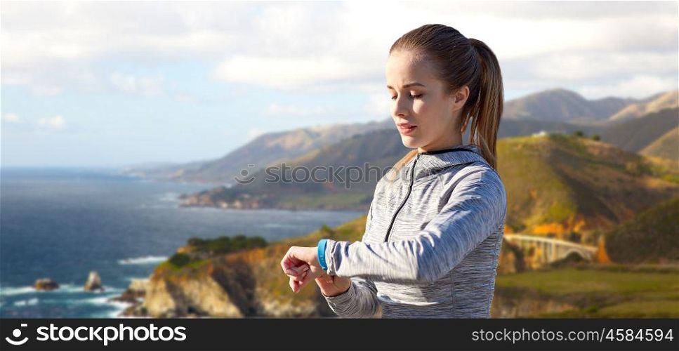 sport, people and technology concept - woman with fitness tracker training over bixby creek bridge on big sur coast of california background. woman with fitness tracker training over big sur. woman with fitness tracker training over big sur