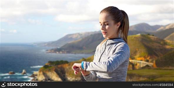 sport, people and technology concept - woman with fitness tracker training over bixby creek bridge on big sur coast of california background. woman with fitness tracker training over big sur. woman with fitness tracker training over big sur
