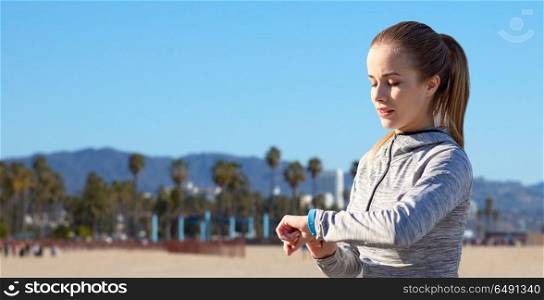 sport, people and technology concept - woman with fitness tracker training over venice beach background in california. woman with fitness tracker training outdoors. woman with fitness tracker training outdoors