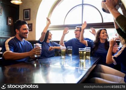 sport, people, friendship and entertainment concept - happy football fans or friends drinking beer, making high five and celebrating victory at bar or pub