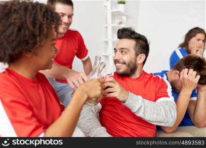 sport, people, friendship and entertainment concept - happy football fans or friends drinking beer and celebrating victory at home