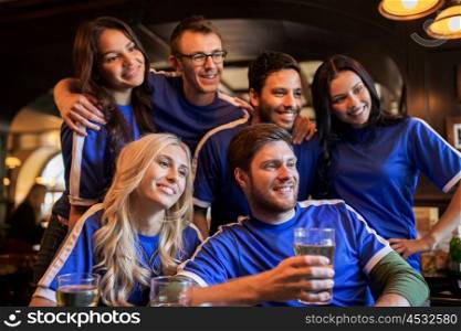 sport, people, leisure, friendship and entertainment concept - happy football fans or friends drinking beer at bar or pub