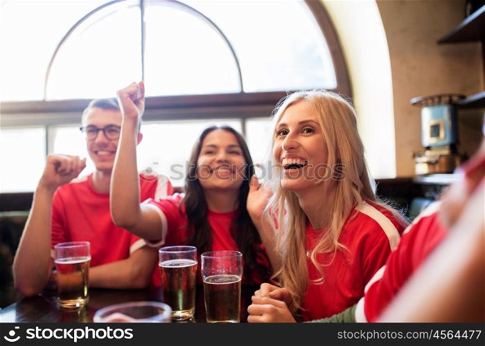 sport, people, leisure, friendship and entertainment concept - happy football fans or friends drinking beer and celebrating victory at bar or pub