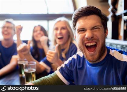 sport, people, leisure, friendship and entertainment concept - happy football fans or friends drinking beer and celebrating victory at bar or pub