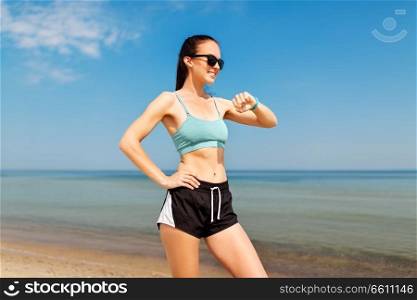 sport, people, technology and healthy lifestyle concept - smiling young woman with fitness tracker on summer beach. happy woman with fitness tracker on summer beach