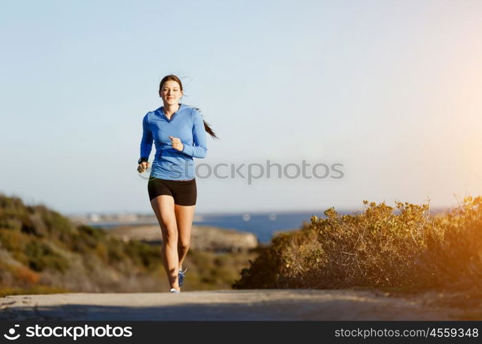 Sport runner jogging on beach working out. Fit female fitness model jogging along ocean