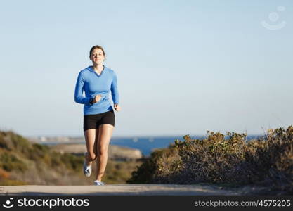 Sport runner jogging on beach working out. Fit female fitness model jogging along ocean