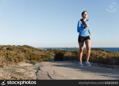 Sport runner jogging on beach working out. Fit female fitness model jogging along ocean