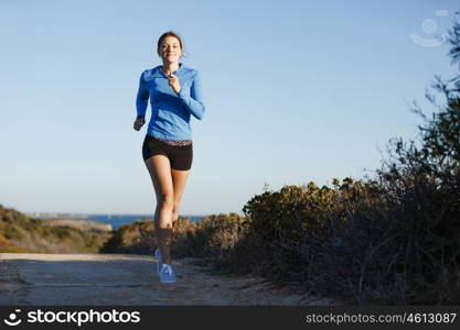 Sport runner jogging on beach working out. Fit female fitness model jogging along ocean