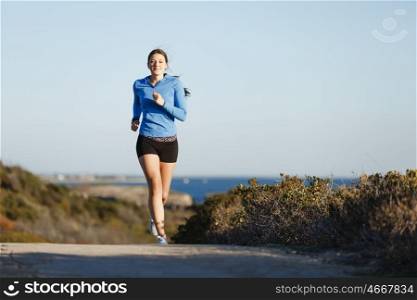 Sport runner jogging on beach working out. Fit female fitness model jogging along ocean