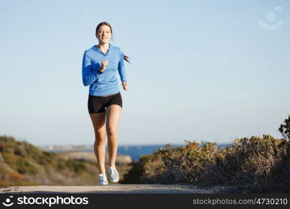 Sport runner jogging on beach working out. Fit female fitness model jogging along ocean