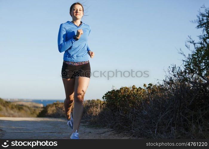 Sport runner jogging on beach working out. Fit female fitness model jogging along ocean