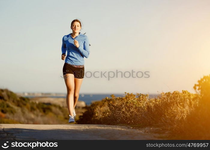 Sport runner jogging on beach working out. Fit female fitness model jogging along ocean