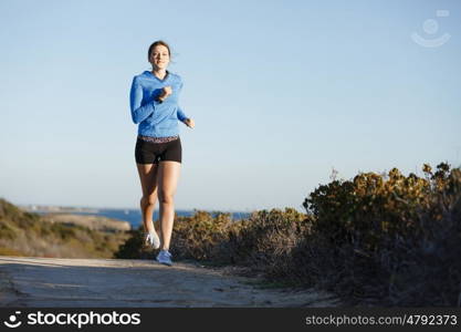 Sport runner jogging on beach working out. Fit female fitness model jogging along ocean