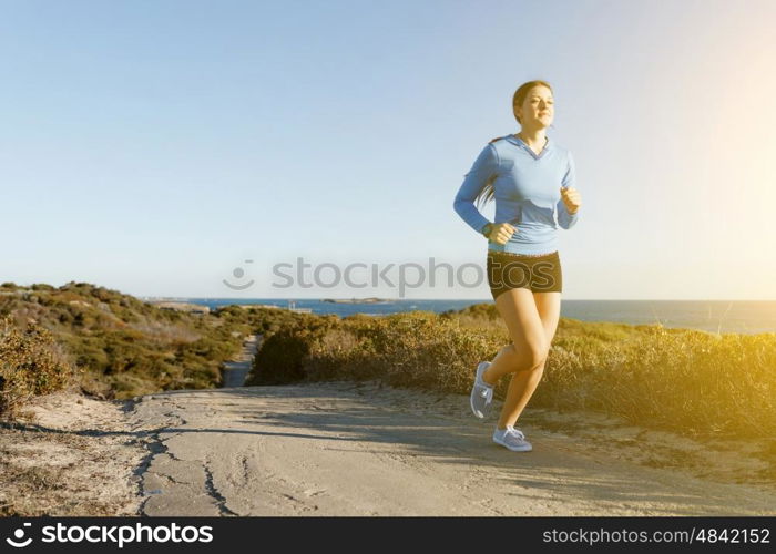 Sport runner jogging on beach working out. Fit female fitness model jogging along ocean