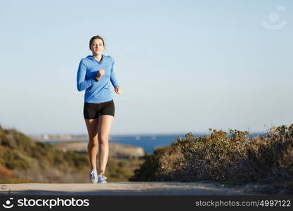 Sport runner jogging on beach working out. Fit female fitness model jogging along ocean