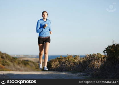 Sport runner jogging on beach working out. Fit female fitness model jogging along ocean