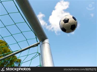 sport, soccer and game - ball flying into football goal net over blue sky. soccer ball flying into football goal net over sky