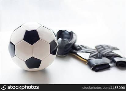 sport, soccer, football and sports equipment concept - close up of ball, boots and goalkeeper gloves on table
