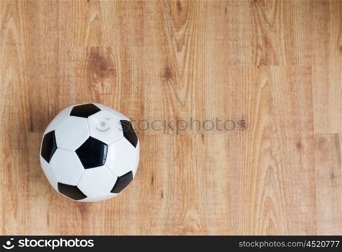 sport, soccer, football and sports equipment concept - close up of ball on wooden floor from top