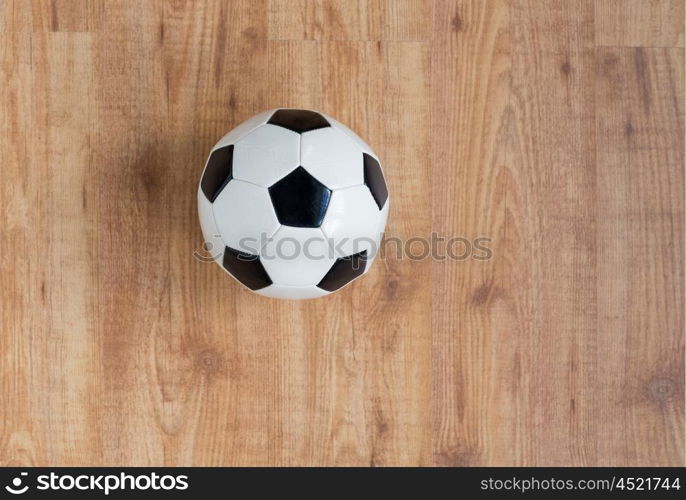 sport, soccer, football and sports equipment concept - close up of ball on wooden floor from top