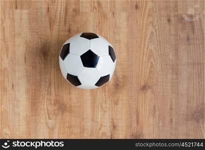 sport, soccer, football and sports equipment concept - close up of ball on wooden floor from top